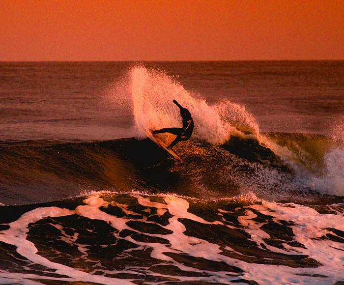Persona haciendo surf en el atardecer | La Brava Surf Schol| Beneficios MP