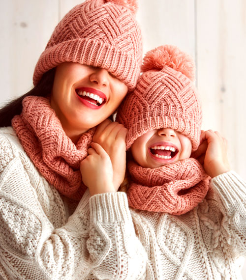 madre e hija con gorros de lana y bufanda, sonriendo