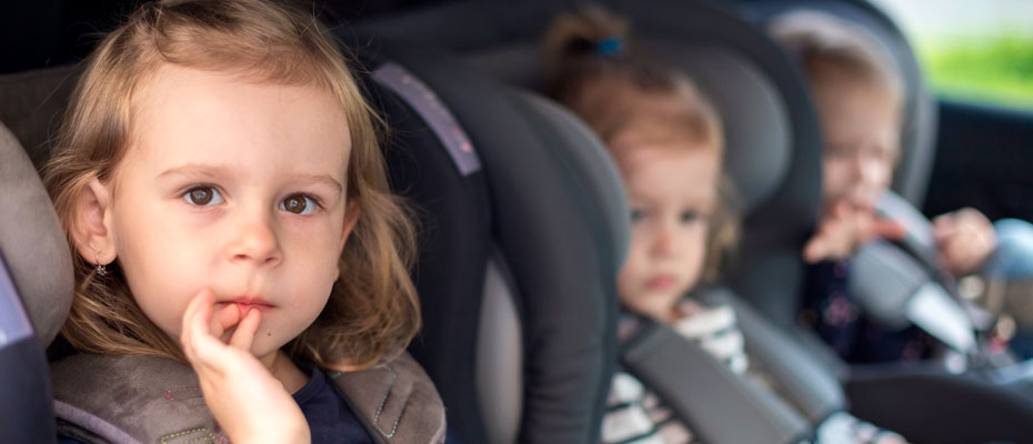 Niños sentados en sillas de retención infantil en un auto