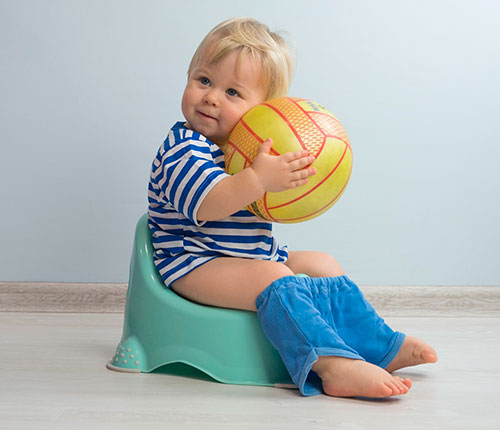 Niño sentando en una pelela con una pelota en la mano