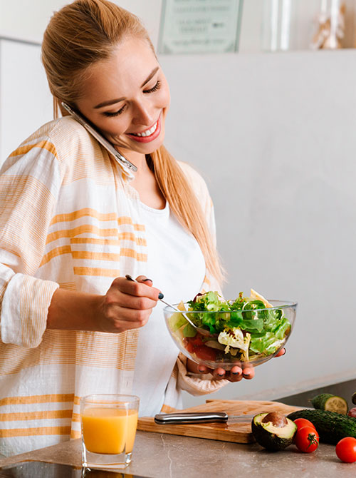 Mujer hablando por celular y preparando una ensalada