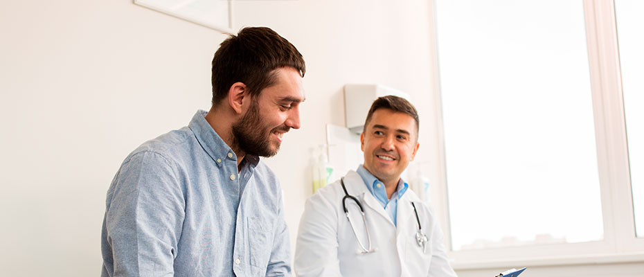 Hombre joven conversando con un médico en un consultorio