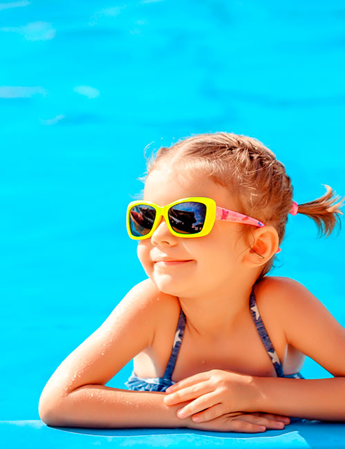 Niña sonriendo en el borde de una piscina 