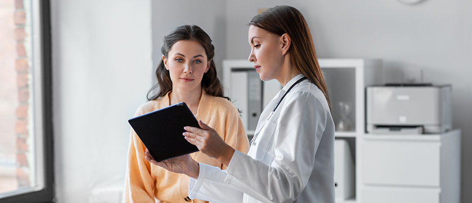 Una doctora le está mostrando una tablet a una paciente sentada en una camilla