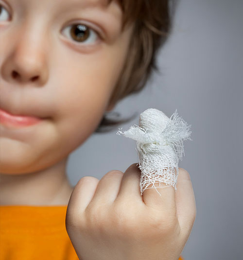 Niño mostrando un dedo vendado - Cómo curar una herida