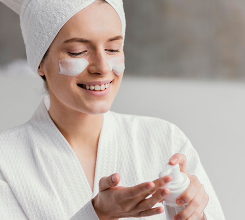 Mujer poniéndose crema facial - Cuidados de la piel