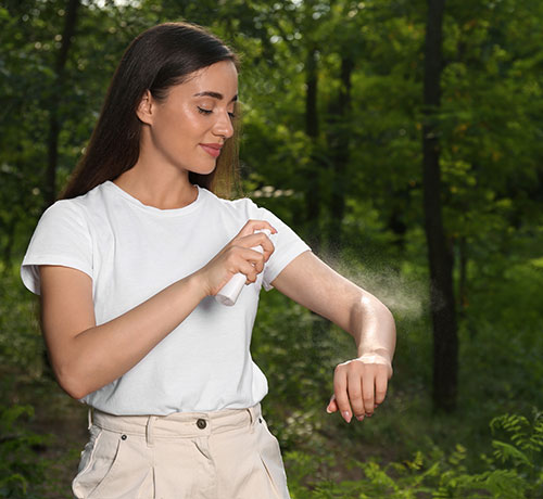 Mujer en un bosque poniéndose repelente de mosquitos