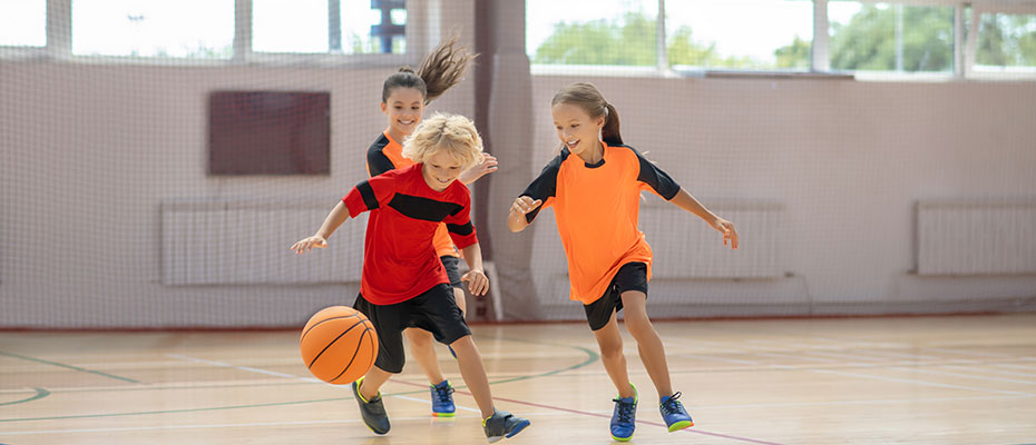 Niños jugando al basketball en una cancha cerrada