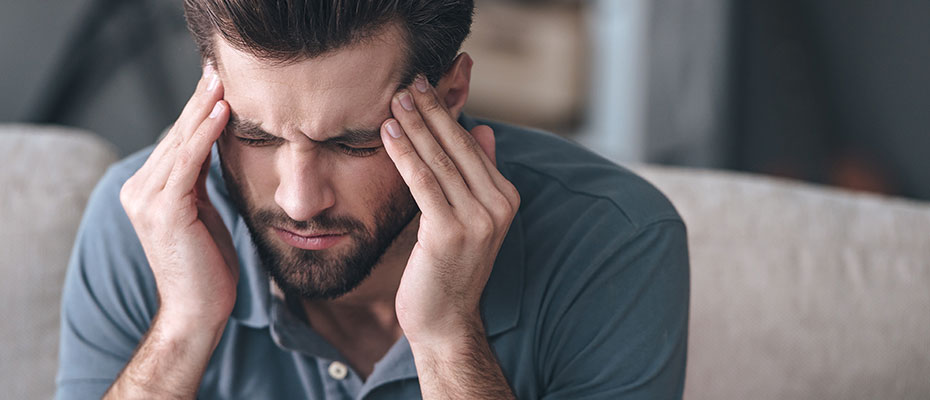 Hombre con las manos en la cabeza por una migraña o cefalea