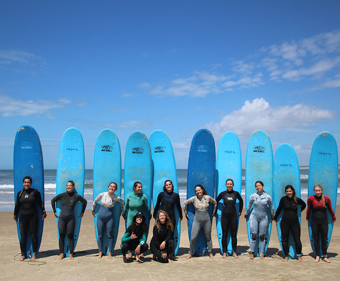 Grupo de mujeres en la playa con tablas de surf en su espalda | Salty Girls | Beneficios MP