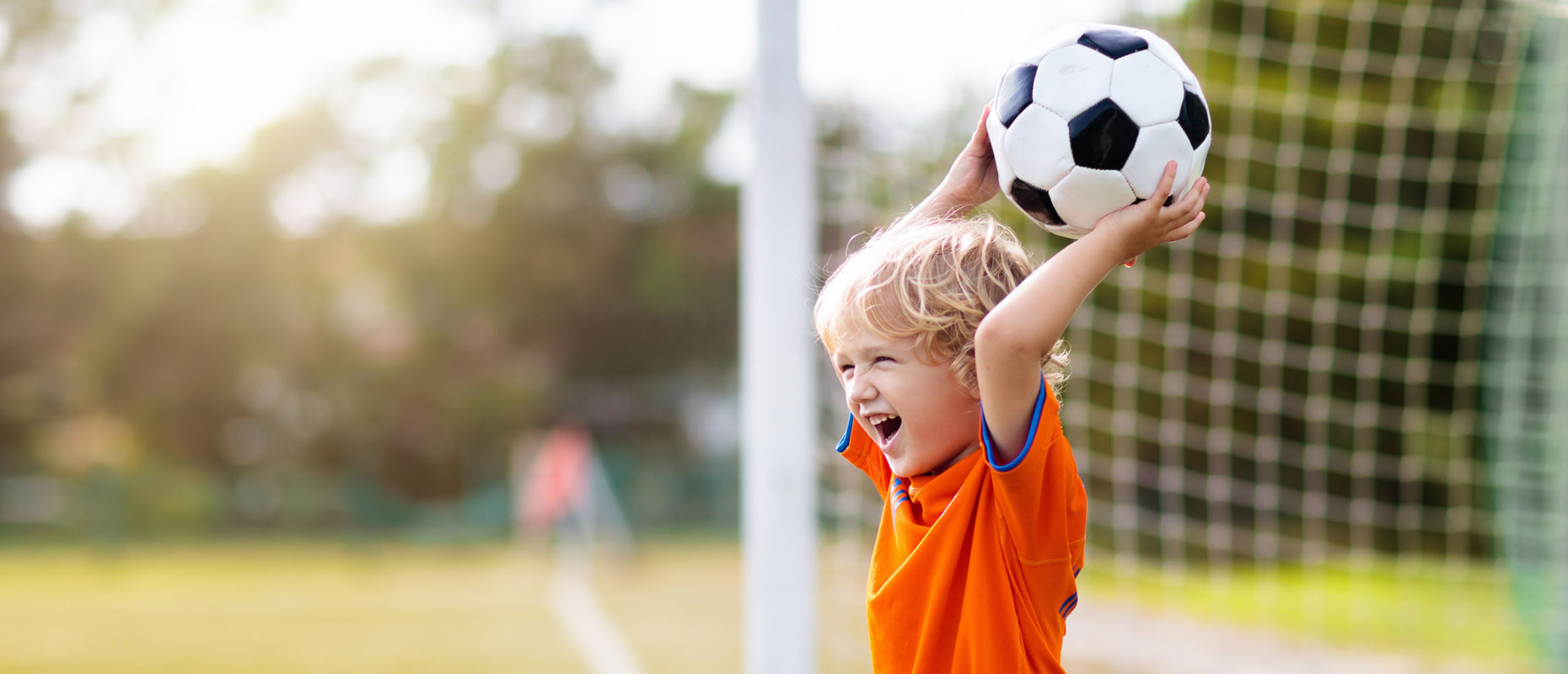 Niño con una pelota de fúbtol en sis manos sobre su cabeza | | Deporte en la infancia: crecer fuertes, felices y saludables Niño con una pelota de fúbtol en sis manos sobre su cabeza | | Deporte en la infancia: crecer fuertes, felices y saludables