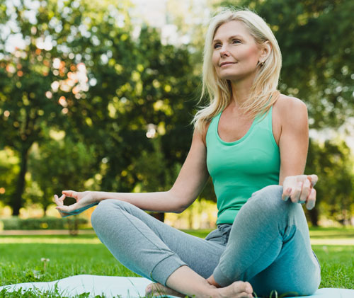 Mujer realizando yoga en un parque | La menopausia no es un final; es evolución Mujer realizando yoga en un parque | La menopausia no es un final; es evolución