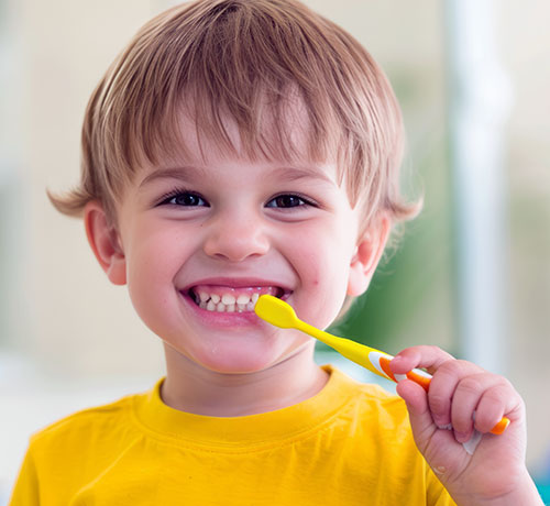 Niño pequeño con un cepillo de dientes en su boca | Salud bucal en niños