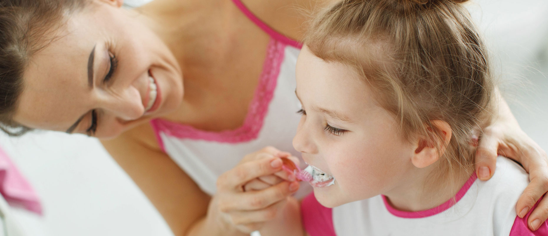 Madre lavándole los dientes a su hija pequeña | Salud bucal en niños