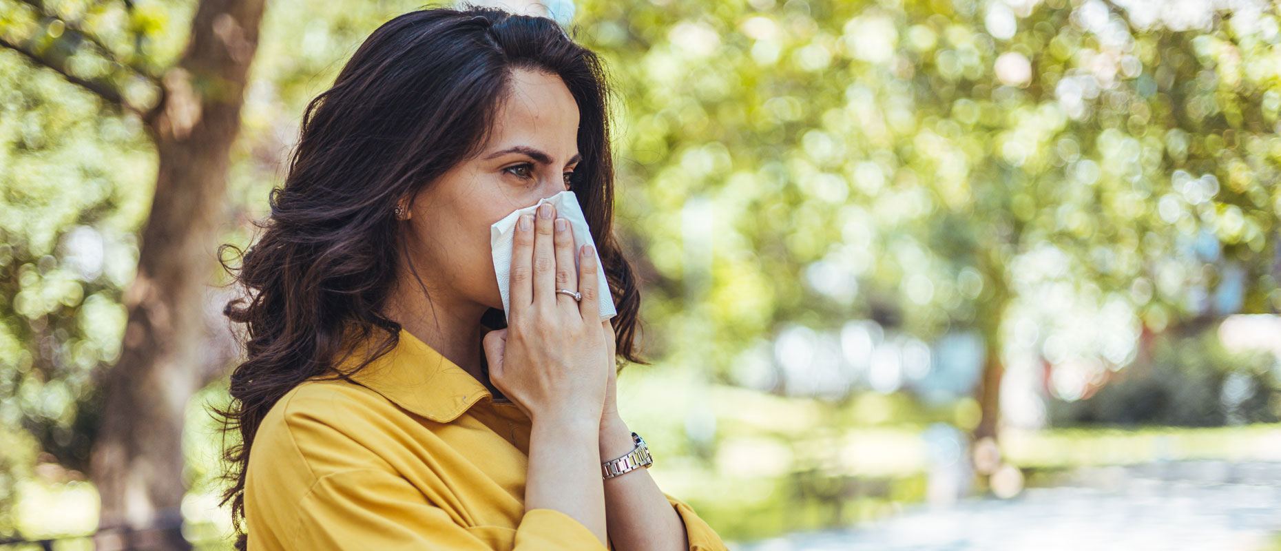 Mujer en un parque con un pañuelo en la nariz | Alergia Mujer en un parque con un pañuelo en la nariz | Alergia