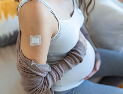 Embarazada con una cinta en el brazo luego de ser vacunada | Vacuna Antigripal Embarazada con una cinta en el brazo luego de ser vacunada | Vacuna Antigripal