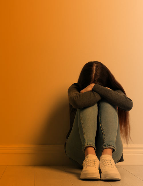 Adolescente sentada en un sillón, triste y su madre hablándole atrás | Conducta alimentaria en la infancia y adolescencia