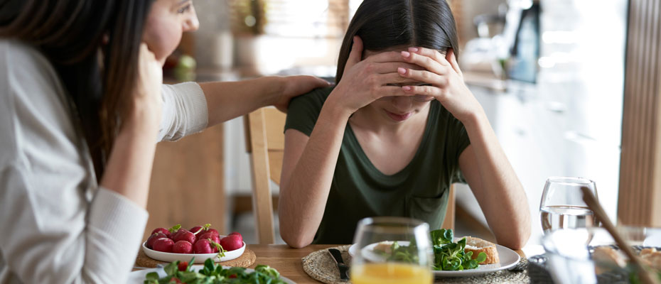mujer desperezándose sentada en una cama frente a una ventana