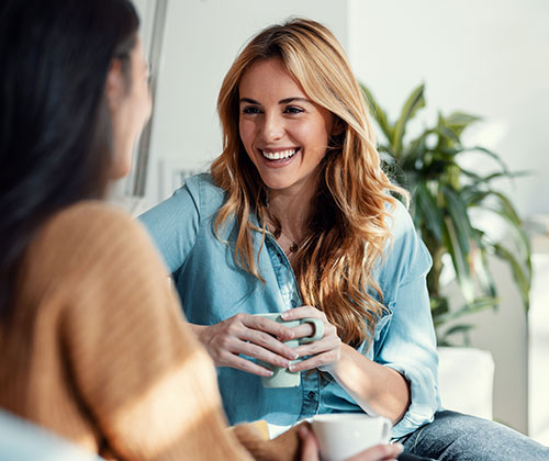Don mujeres conversando | Mujer sonriendo con un vaso de agua en la mano | Endometriosis: entender sus señales para un diagnóstico temprano