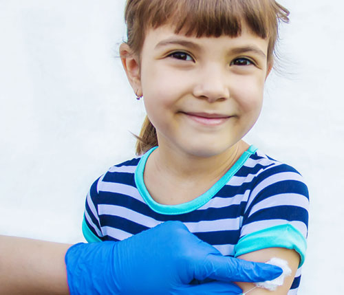 Niña sonriendo mientras recibe una vacuna en su brazo | Uruguay libre de Sarampión