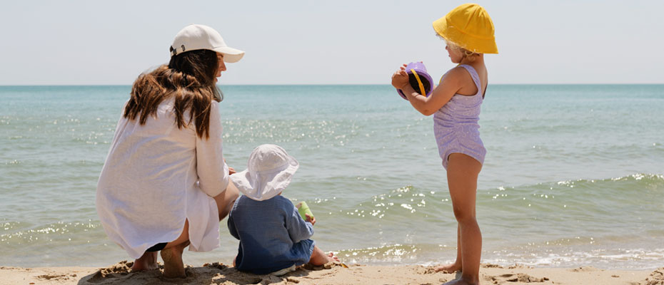 Madre con hijas chicas jugando en la playa a la orilla del mar | Vacaciones: tiempo de jugar