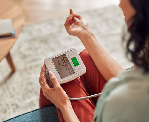 Mujer controlándose la presión con un medidor eléctrico | La importancia de controlar la presión arterial a tiempo