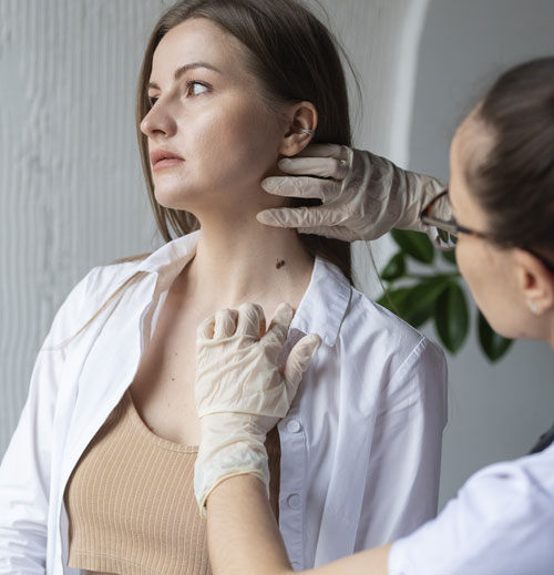 Doctora controlando un lunar en el cuello de una mujer | El cuidado de la piel, un hábito para todo el año