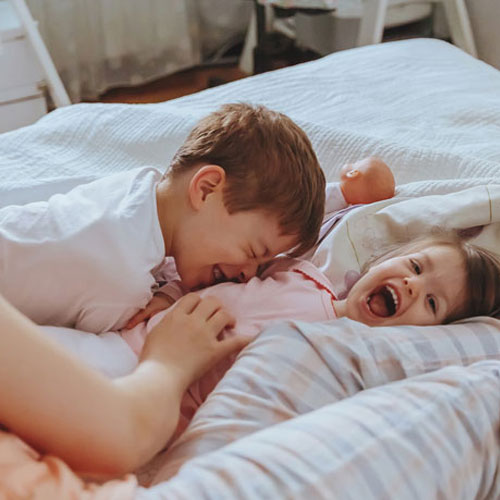 Niños chicos riendo en la cama junto con su madre | Gracias por la mirada