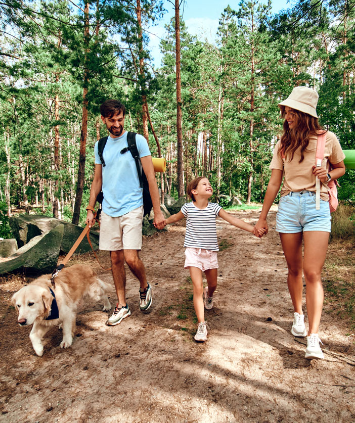 Familia con una niña caminando en un bosque con un perro | Asistencia en el interior del país