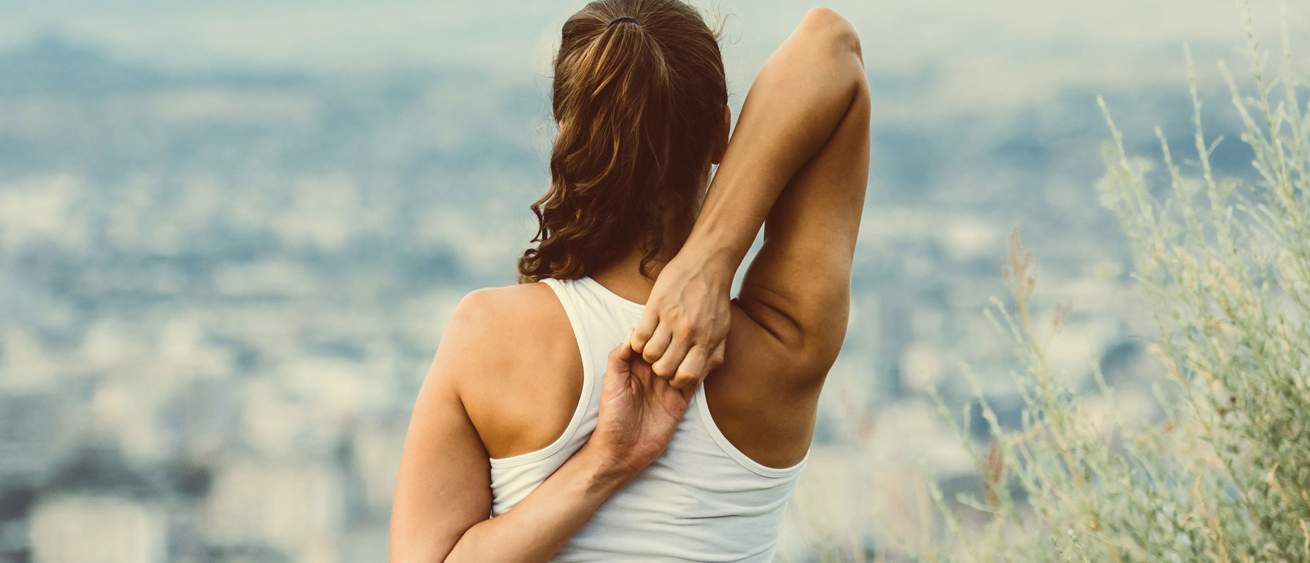 Mujer estirando la espalda al aire libre | Cuidar nuestros huesos: una inversión para toda la vida
