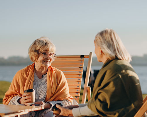 dos Mujeres adultas compartiendo un café al sol | Longevidad saludable