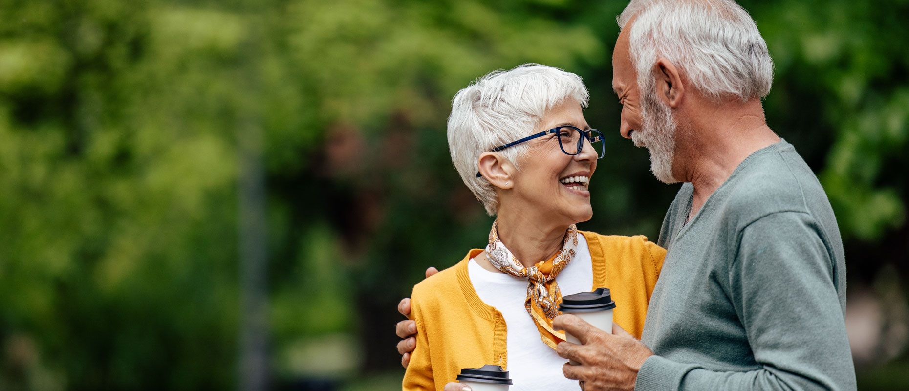 Pareja de adultos mayores en un parque con un vaso de café en la mano | Longevidad saludable